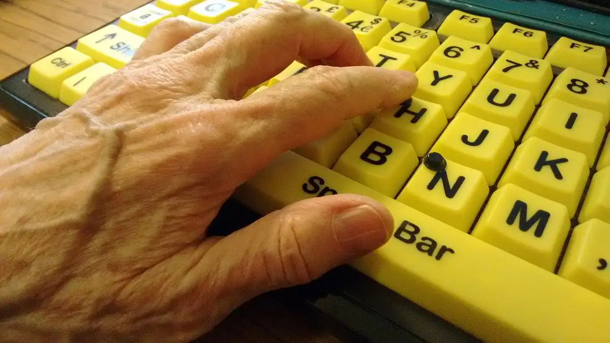 Hand of a partially sighted user on a high-contrast accessible computer keyboard.