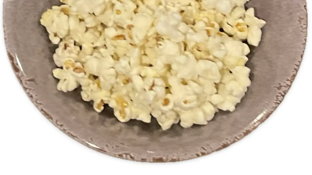 Some popcorn poured out of a bag in a bowl.